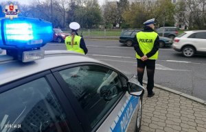 Dwójka umundurowanych policjantów czuwająca nad bezpieczeństwem na drodze