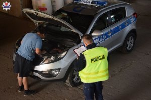 Etap powiatowy Ogólnopolskiego Młodzieżowego Turnieju Motoryzacyjnego zdjęcie pojazdu policyjnego, policjant oceniający przegląd wykonywany uczestnika konkursu