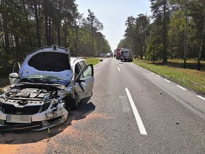 Zdjęcie poglądowe na którym uwidoczniono uszkodzenia po kolizyjne pojazdu Skoda koloru białego. w tle widoczny drugi pojazd.Mercedes.