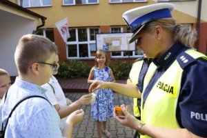 Zdjęcie poglądowe na którym uwidoczniono umundurowanego funkcjonariusza policji z uczniem