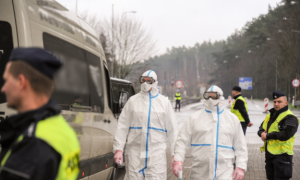 Zdjęcie policjantów umundurowanych oraz dwóch w fartuchach ochronnych i maskach