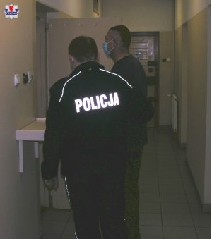 policjant wprowadza osobę podejrzaną w pomieszczeniach dla osób zatrzymanych