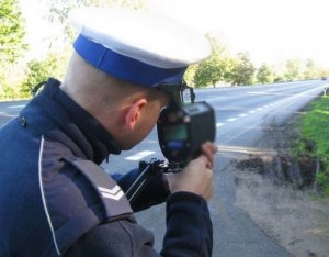 Policjant Ruchu Drogowego podczas mierzenia prędkości na drodze.