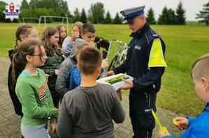 Policjant Ruchu Drogowego rozdaje dzieciom odblaski.