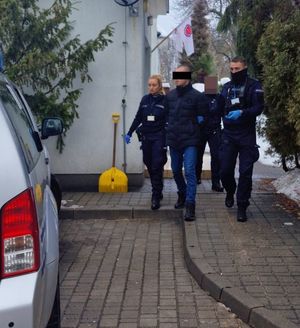 Zdjęcie zatrzymanego prowadzonego przez 2 policjantów