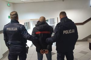 Zdjęcie dwóch umundurowanych policjantów trzymających zatrzymanego