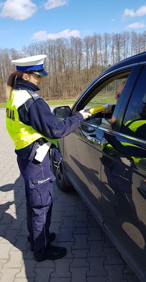 Zdjęcie policjantki badającej stan trzeźwości kierującego ciemnym  pojazdem