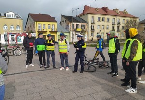 Zdjęcie policjantki ruchu drogowego omawiającej zagadnienie z uczestnikami rajdu rowerowego