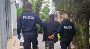 Policjanci prowadzą zatrzymanego mężczyznę.