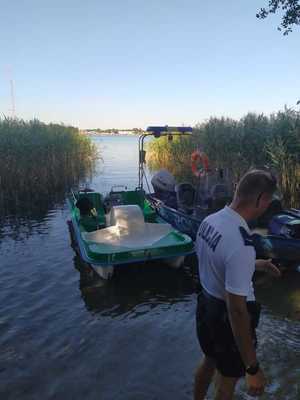 Policjant patrolu wodnego podczas służby w Okunince. W tle jezioro i policyjna łódź oraz rower wodny