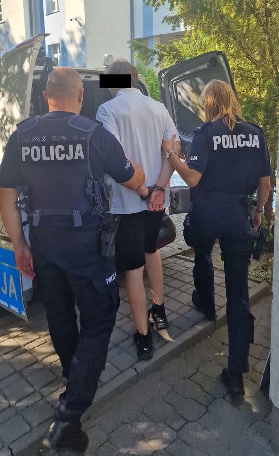 Zdjęcie zatrzymanego prowadzonego przez 2 umundurowanych funkcjonariuszy
