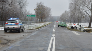 miejsce zdarzenia drogowego, 2 auta z uszkodzeniami w tle radiowóz i wóz strażacki zabezpieczają miejsce zdarzenia