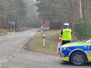 policjant stojący przy radiowozie i patrzący w stronę torów kolejowych