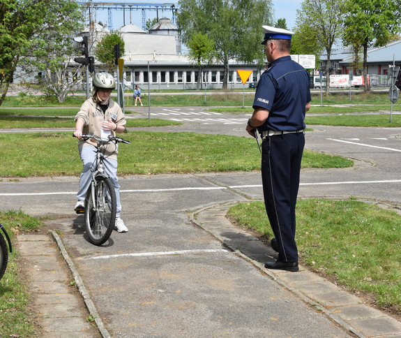 konkurencja miasteczko ruchu drogowego, uczestnik na rowerze obok umundurowany policjant