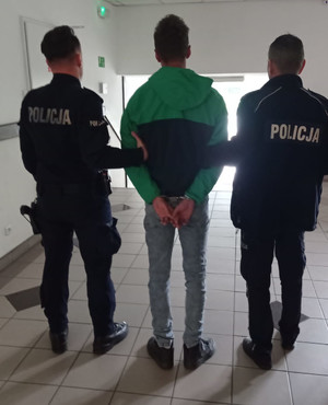 policjanci prowadzą zatrzymanego poszukiwanego w komendzie widok z tyłu