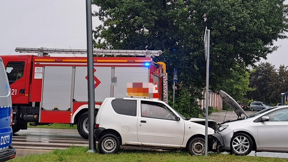 Miejsce kolizji drogowej na ulicy Chełmskiej we Włodawie.Na zdjęciu widoczne są dwa uszkodzone po czołowym zderzeniu samochody marki Toyota Auris koloru srebrnego i biały Fiat Seicento oraz czerwony wóz strażacki i oznakowany radiowóz policyjny
