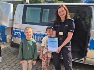 policjantka z dziećmi trzyma w ręku podziękowanie