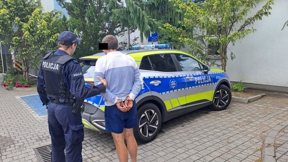 policjant stoi z zatrzymanym