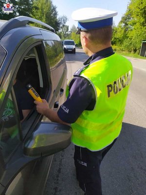 Zdjęcie przedstawia funkcjonariusza badającego stan trzeźwości kierującego
