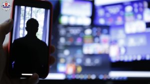 Zdjęcie trzymanego w dłoni telefonu ze zdjęciem odwróconej postaci na wyświetlaczu i fragmentu okna