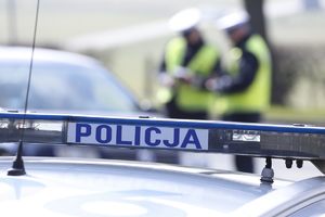 belka oświetleniowa na dachu z napisem Policja w tle policjanci