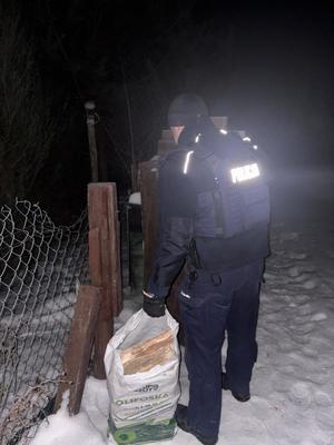 zdjęcie przedstawiające policjant niosącego worek z drewnem opałowym