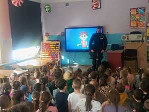 zdjęcie policjanta w trakcie omawiania filmu instruktażowego o bezpieczeństwie podczas ferii