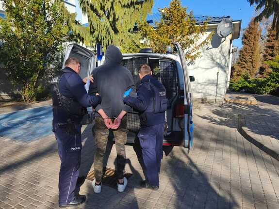 zdjęcie przedstawiające dwóch policjantów którzy są w trakcie realizacji doprowadzenia osoby poszukiwanej do zakładu karnego