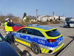 zdjęcie przedstawiające policjanta w trakcie służby wykorzystującego lornetkę w celu sprawdzenia przestrzegania obowiązku korzystania z pasów bezpieczeństwa