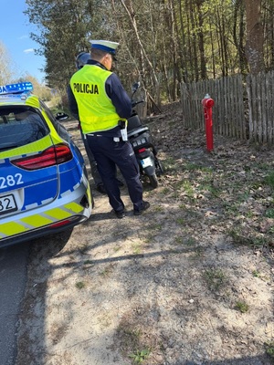 Zdjęcie przedstawiające policjanta kontrolującego motorowerzystę