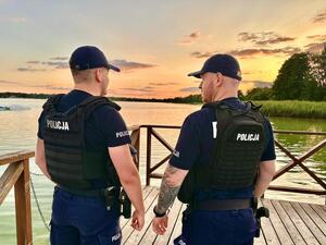 zdjęcie przedstawia dwóch policjantów pełniących służbę nad akwenem wodnych po