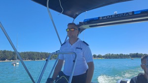 zdjęcie przedstawia wizerunek policjanta podczas patrolowania akwenu wodnego łodzią policyjną
